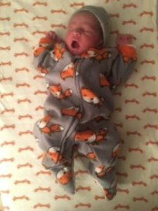 a yawning baby in a printed onesie