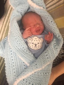 a newborn wrapped in a knitted blanket